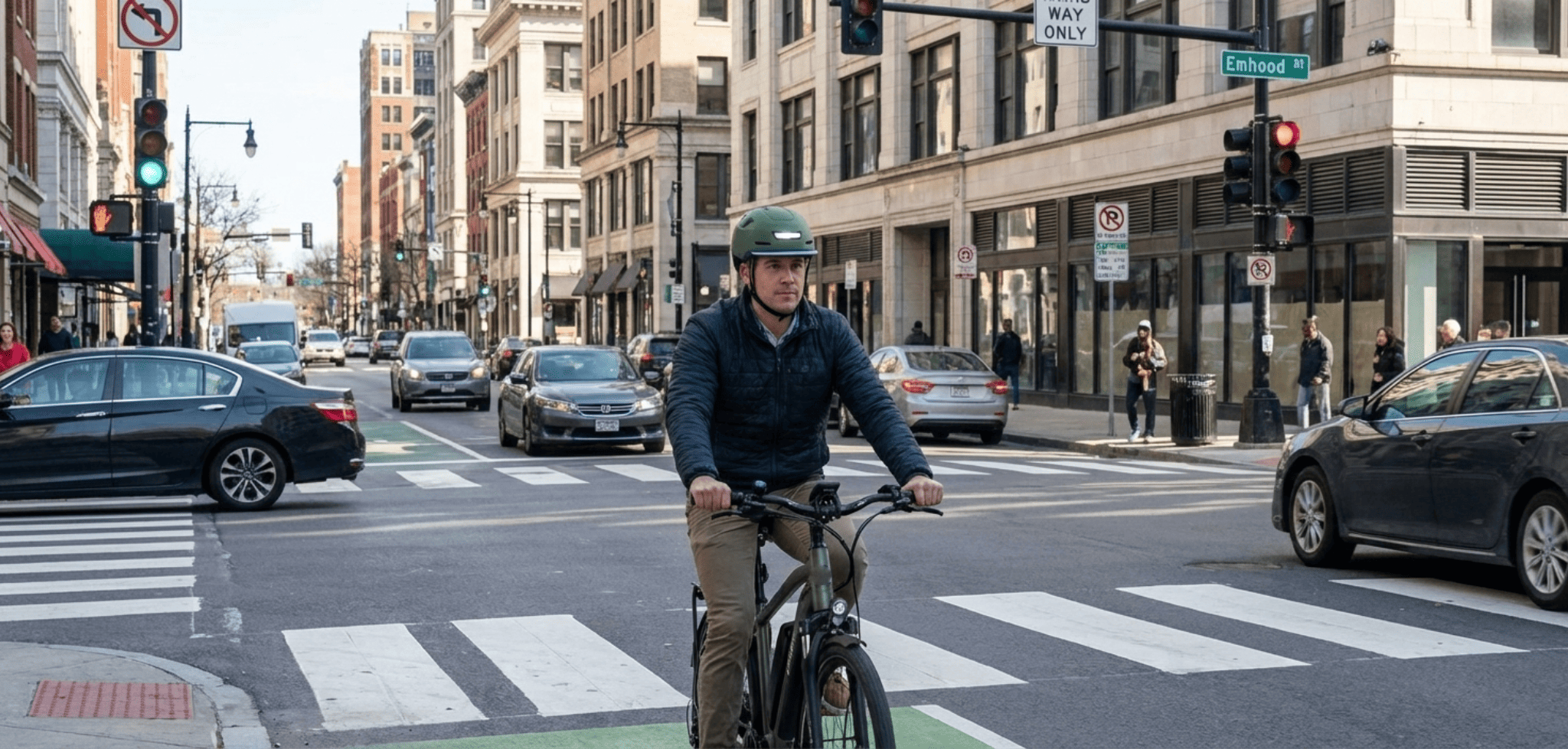An eBike rider wearing an XNITO helmet approaching a busy city intersection with turning cars in the background