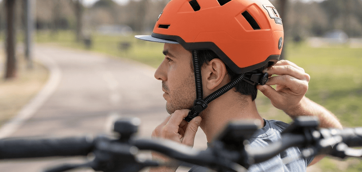 eBike rider adjusting the XNITO helmet straps and rear dial-fit system before riding