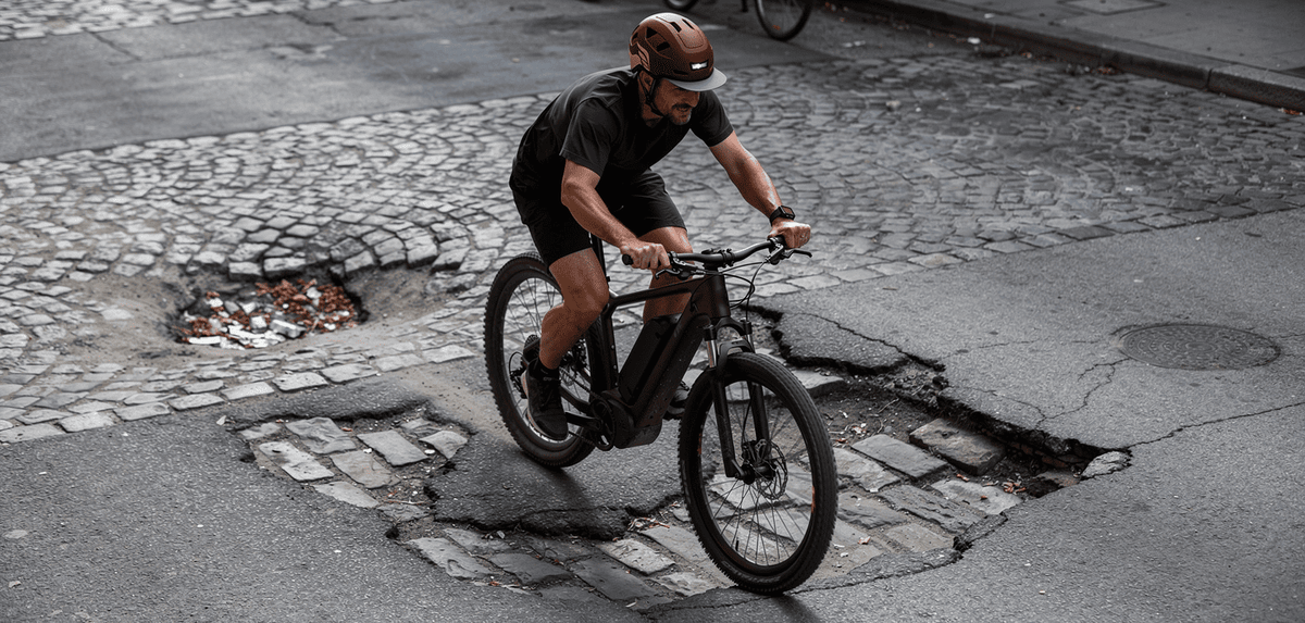 eBike rider wearing an XNITO helmet going over a rough city street with visible potholes or cobblestones